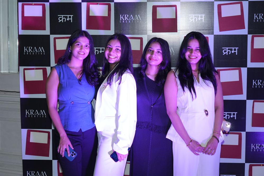 Four of the KRAM Creative team at the launch backdrop under stage lighting