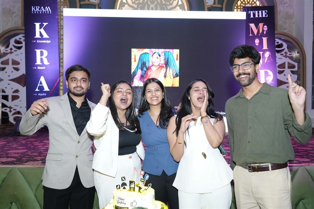 Five of the KRAM Creative team cheering around a cake at the launch