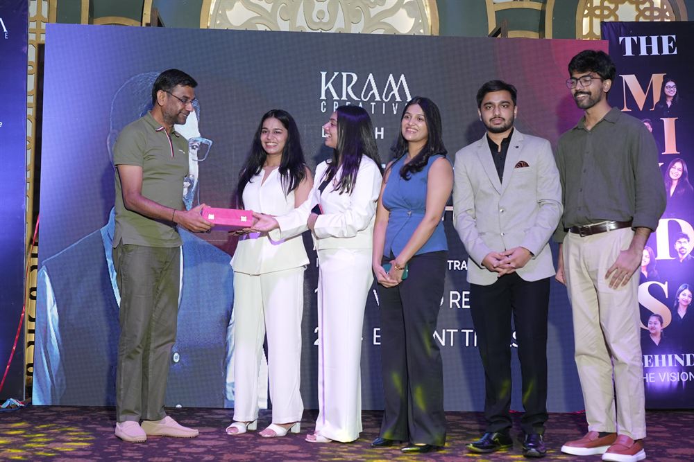 A guest being handed a gift on stage by the KRAM Creative team at the launch