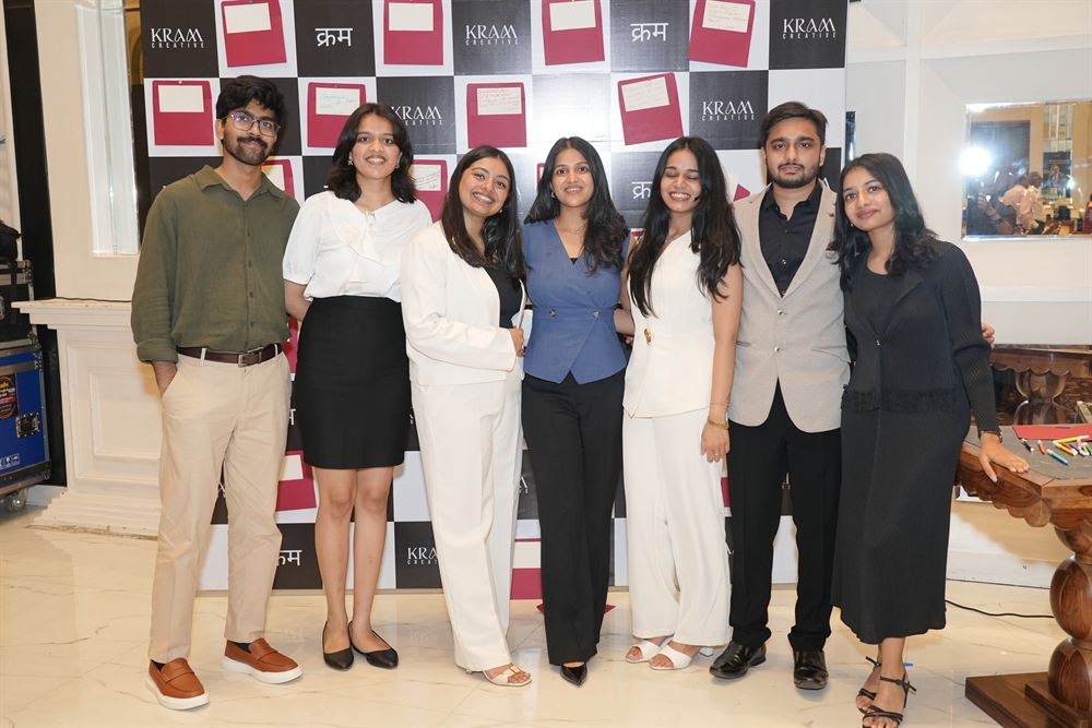 Seven members of the KRAM Creative team at the branded launch backdrop
