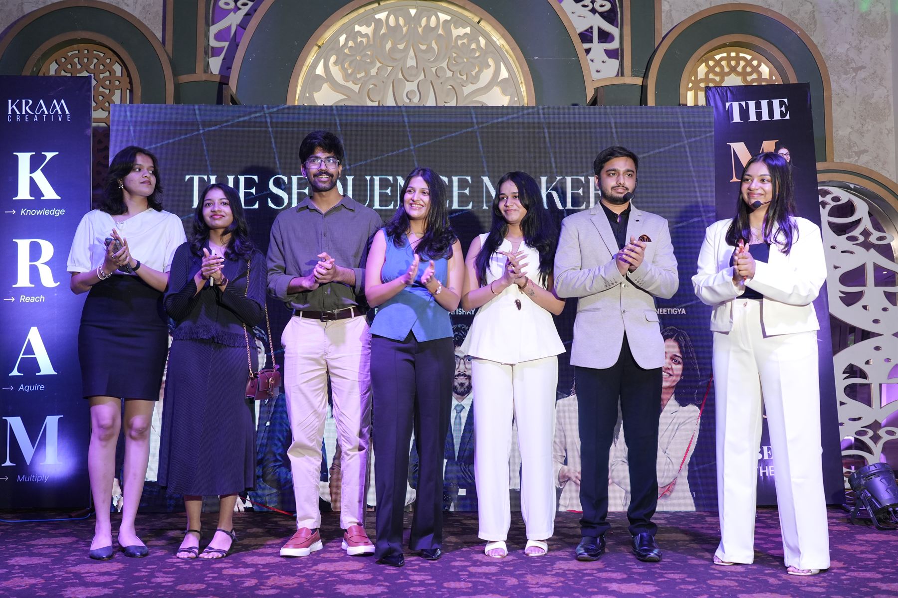 The KRAM Creative team applauding on stage beneath a screen reading The Sequence Makers